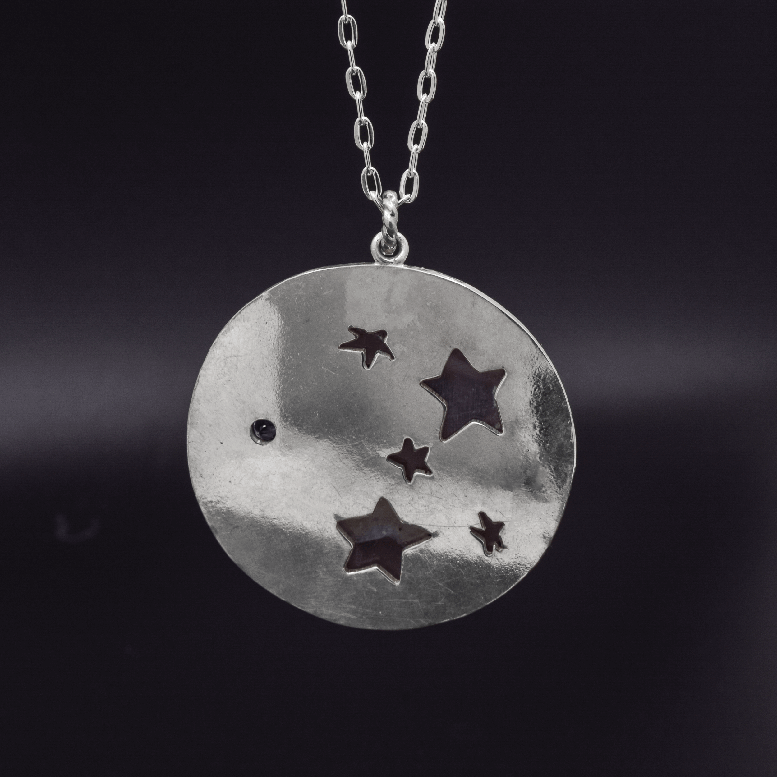 back of sterling silver circle pendant with pierced stars hanging on a cable chain