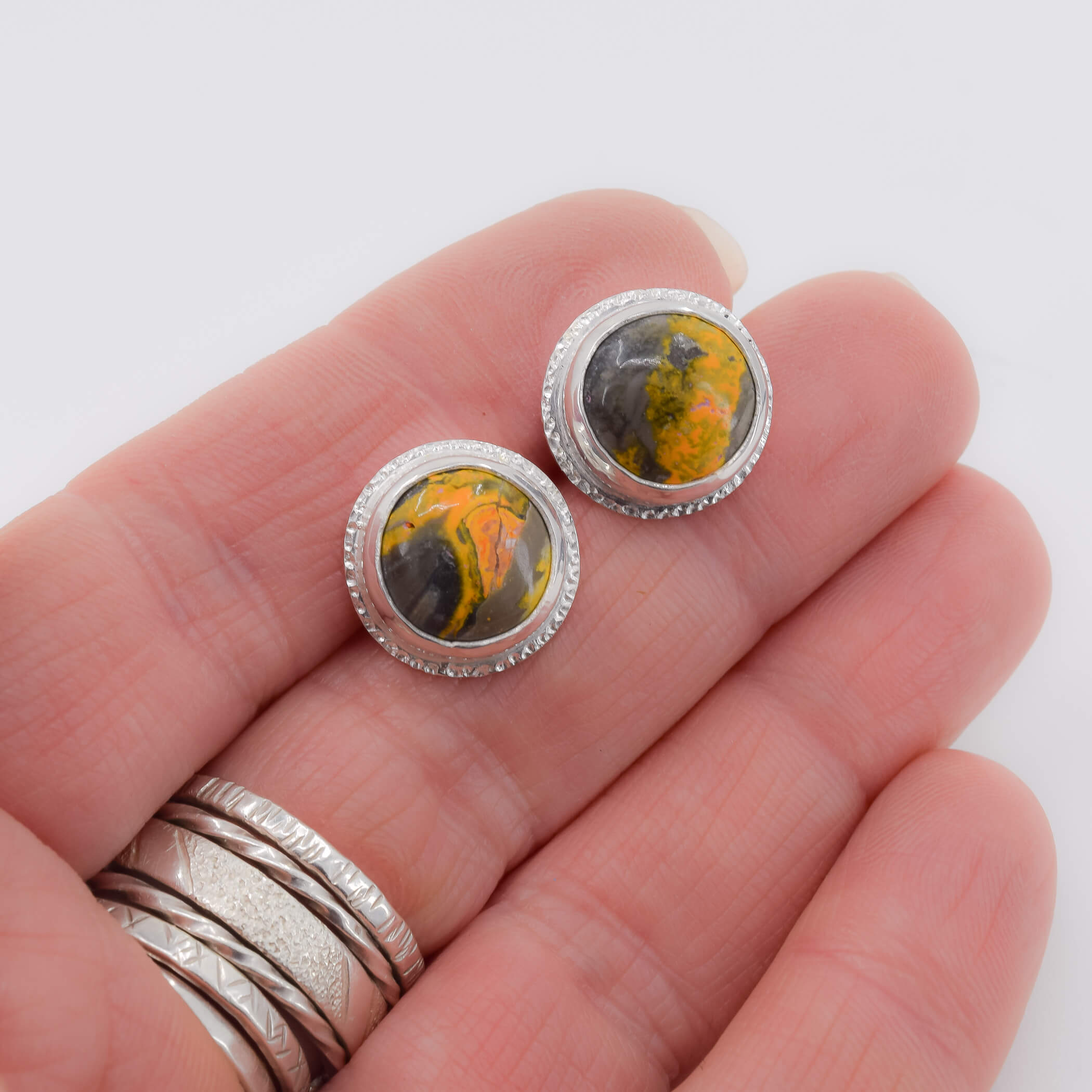 Round bumblebee jasper stud earrings in sterling silver shown in hand for scale