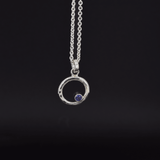 Circle of life iolite pendant necklace sterling silver hanging from a cable chain on a black background