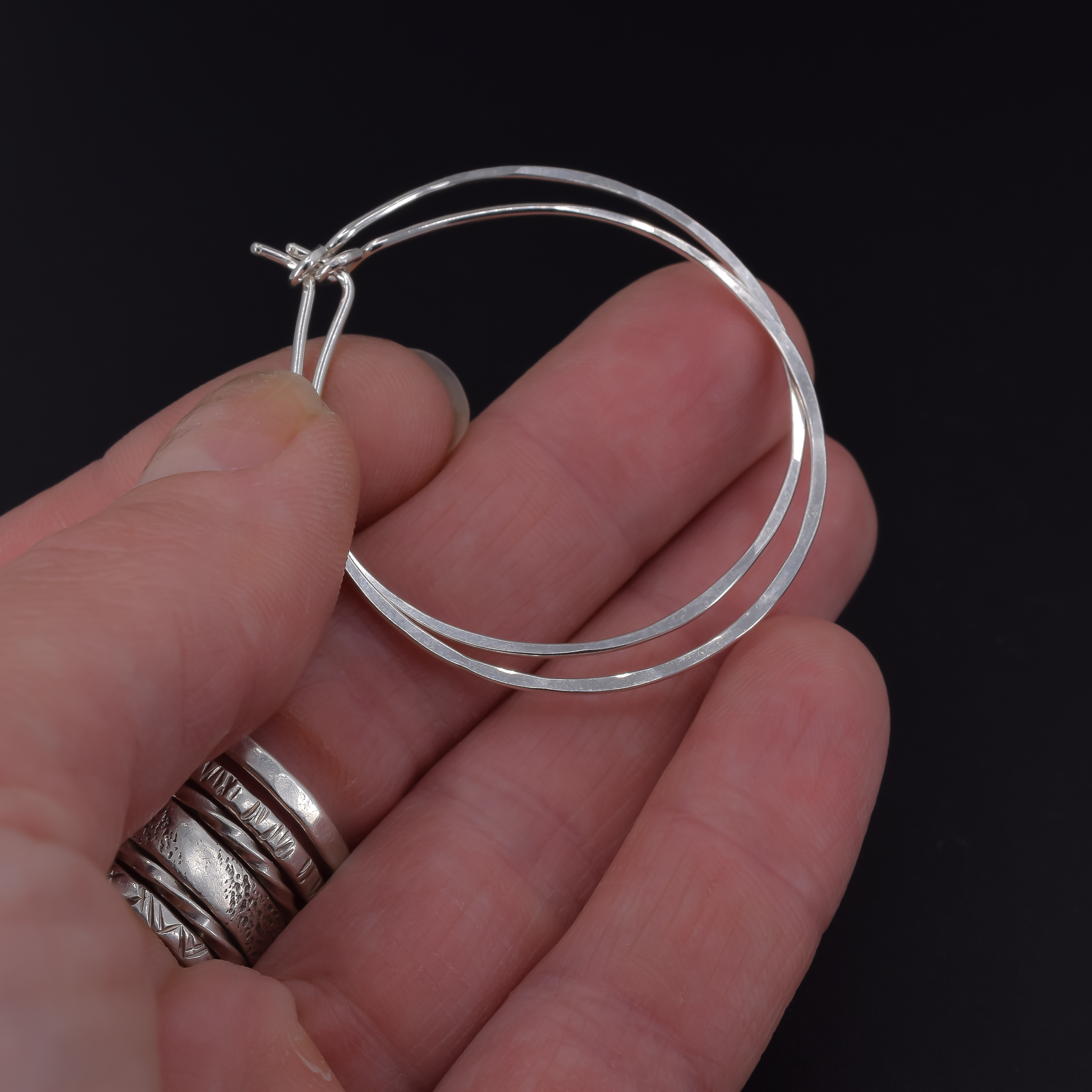 Medium 1.5 inch sterling silver hoop earrings shown in hand
