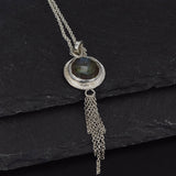 a round labradorite pendant necklace in sterling silver, which has a chain embellishment on the bottom on a slate background
