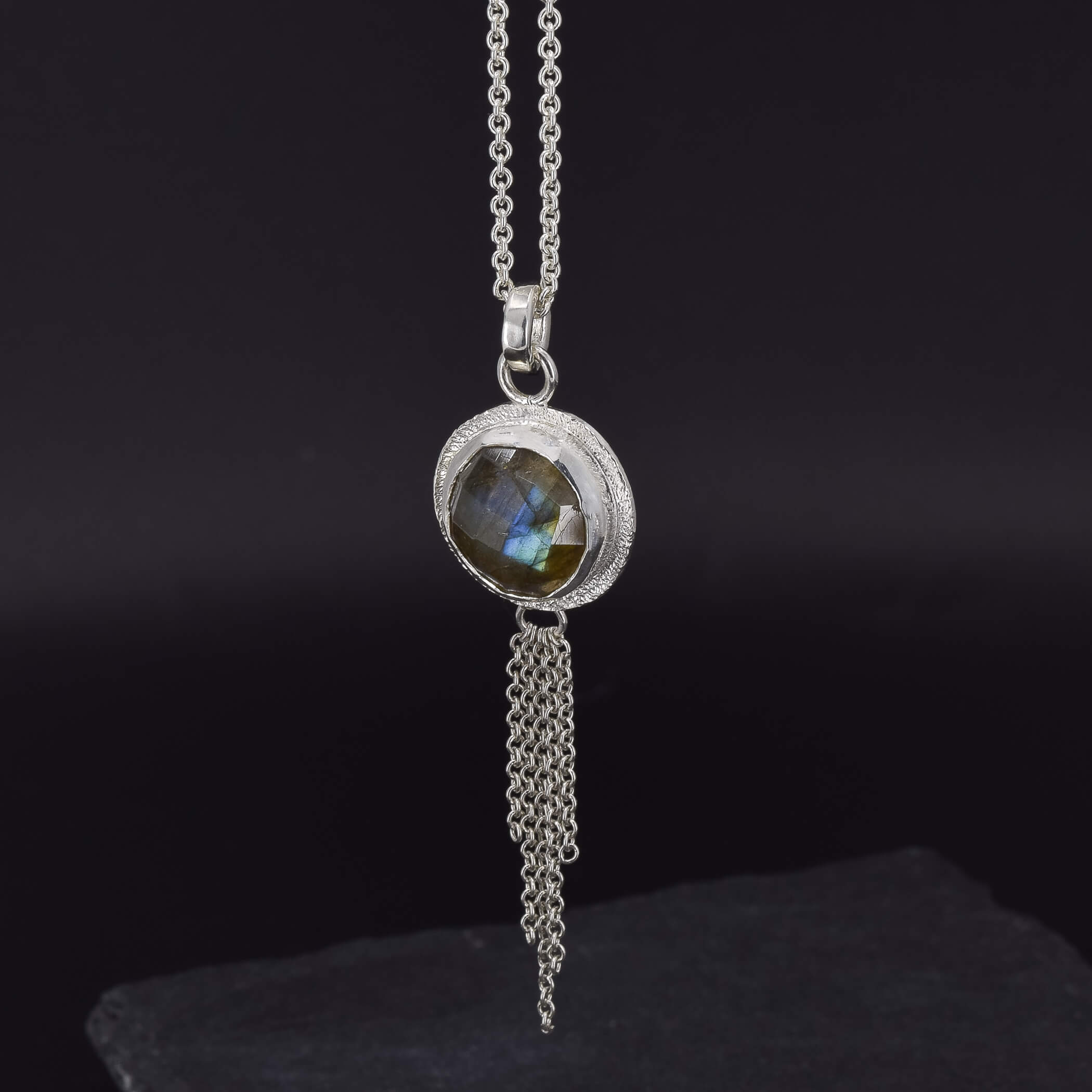 side view of the design on the back of a round labradorite pendant necklace in sterling silver, which has a chain embellishment on the bottom