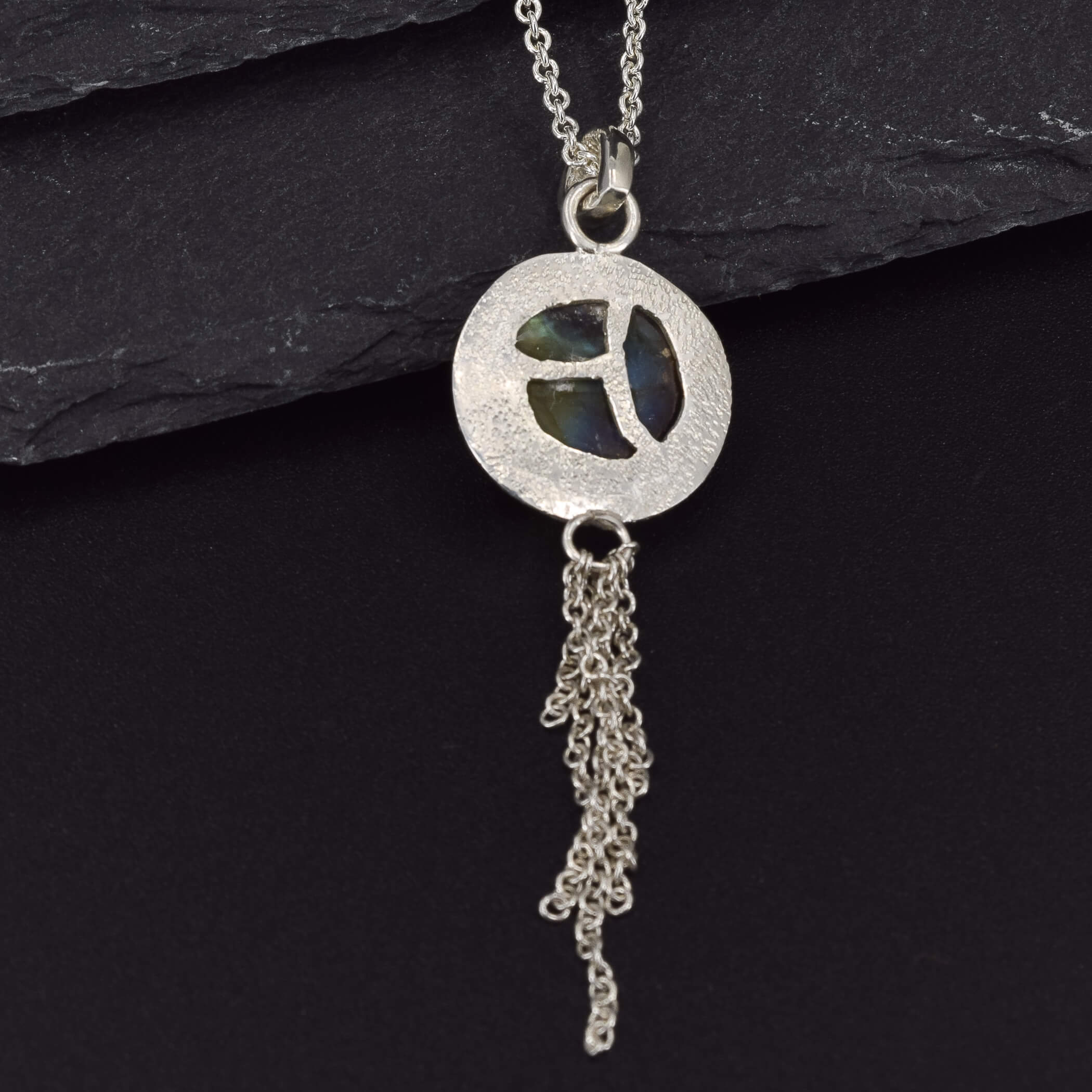 view of the design on the back of a round labradorite pendant necklace in sterling silver, which has a chain embellishment on the bottom