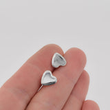 Stardust engraved heart studs earrings in sterling silver shown in hand for scale