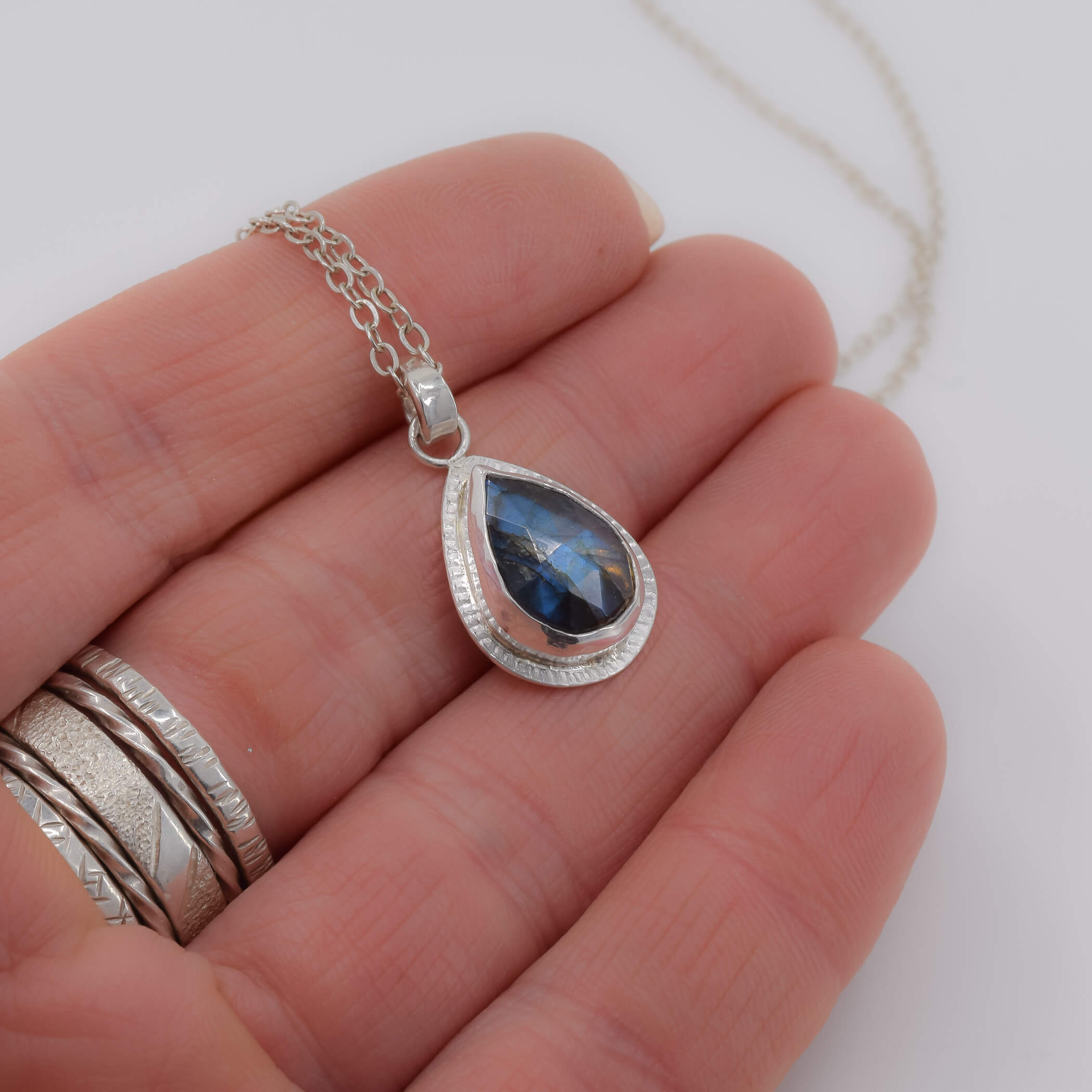 teardrop labradorite pendant necklace in sterling silver shown in hand for scale