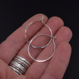 Extra small 1 inch sterling silver hoop earrings shown in hand