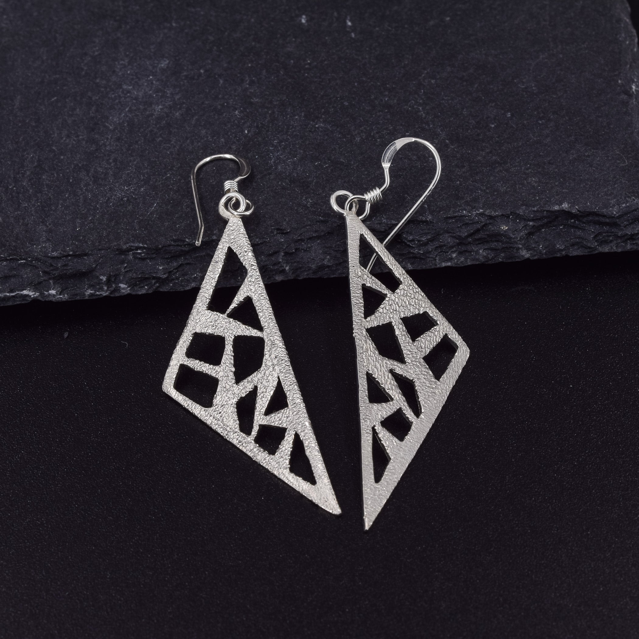 Triangle dangle earrings in sterling silver pierced with a modern design with a textured stardust finish