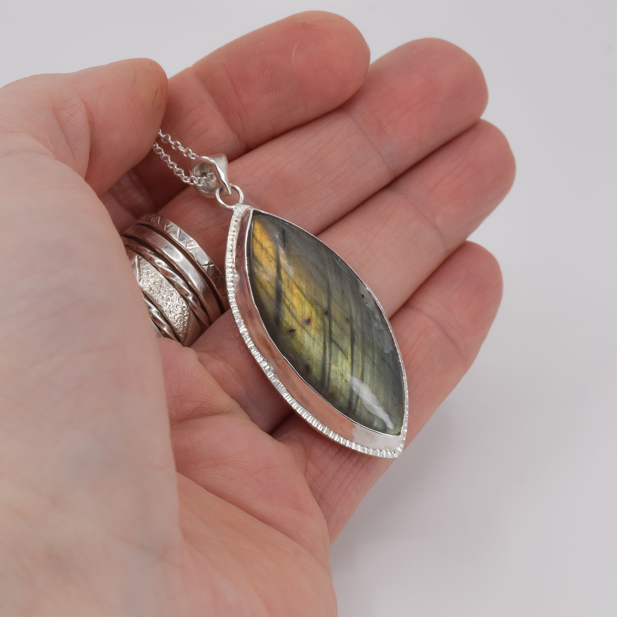 Yellow and green labradorite sterling silver pendant necklace held in hand