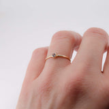 thin 14K yellow gold stacking ring with white sapphire shown on hand