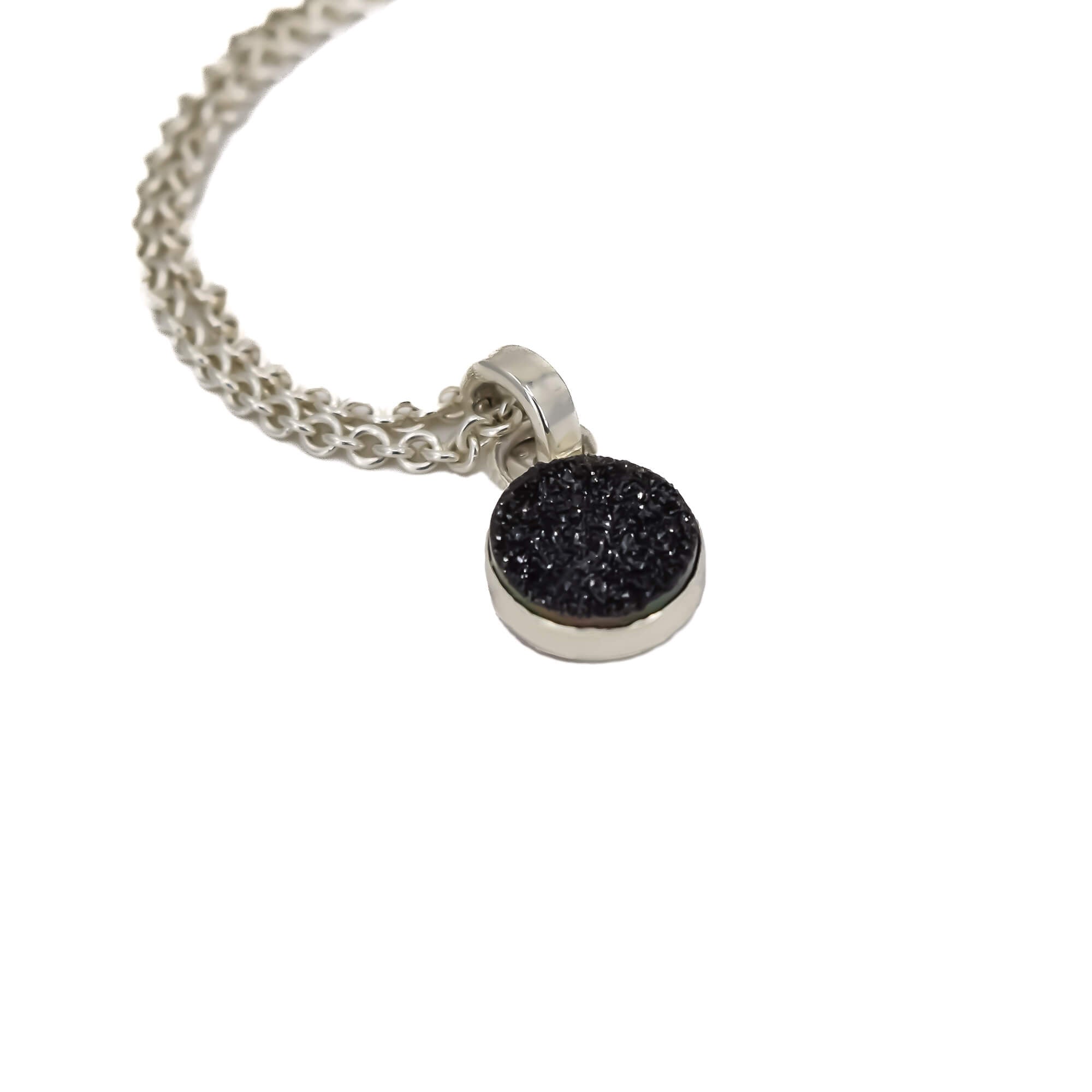 Side view of small round black druzy pendant set in sterling silver hanging on a cable chain
